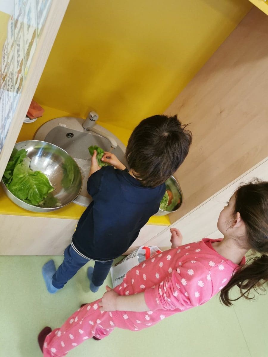 Copii spălând legume la chiuveta de la înălțimea lor