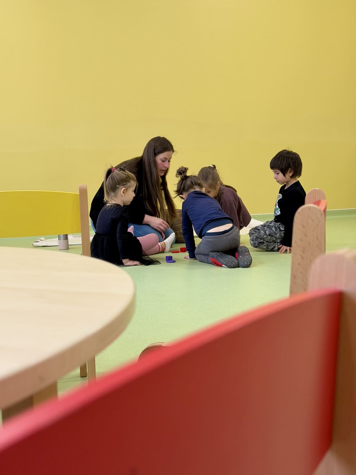 Educatoare jucându-se cu copiii în sala de grupă
