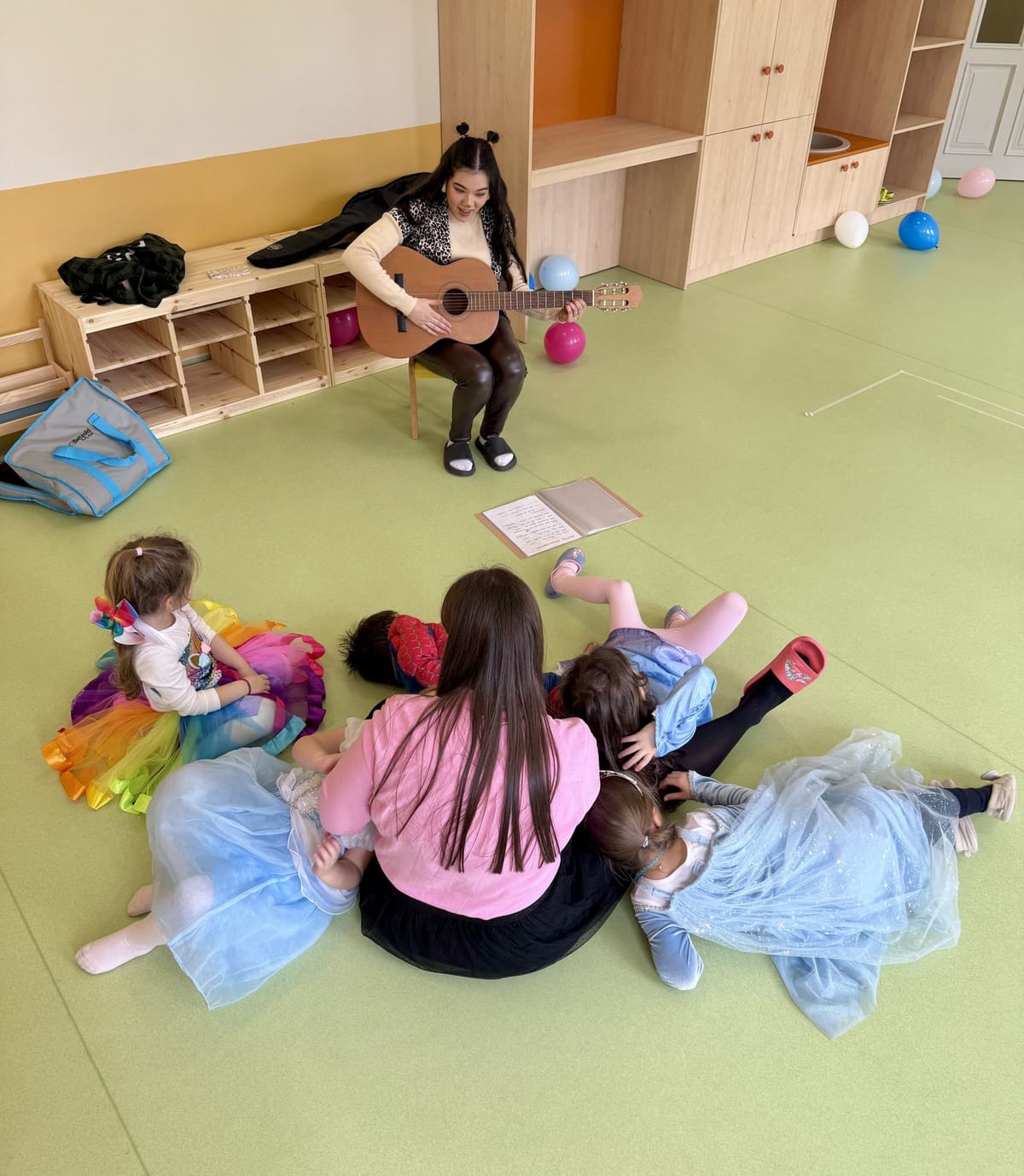 Educatoare cântând la chitară pentru copii